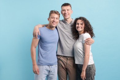 Photo of Three friends hugging on light blue background