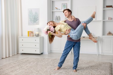 Photo of Happy young couple dancing together at home. Space for text