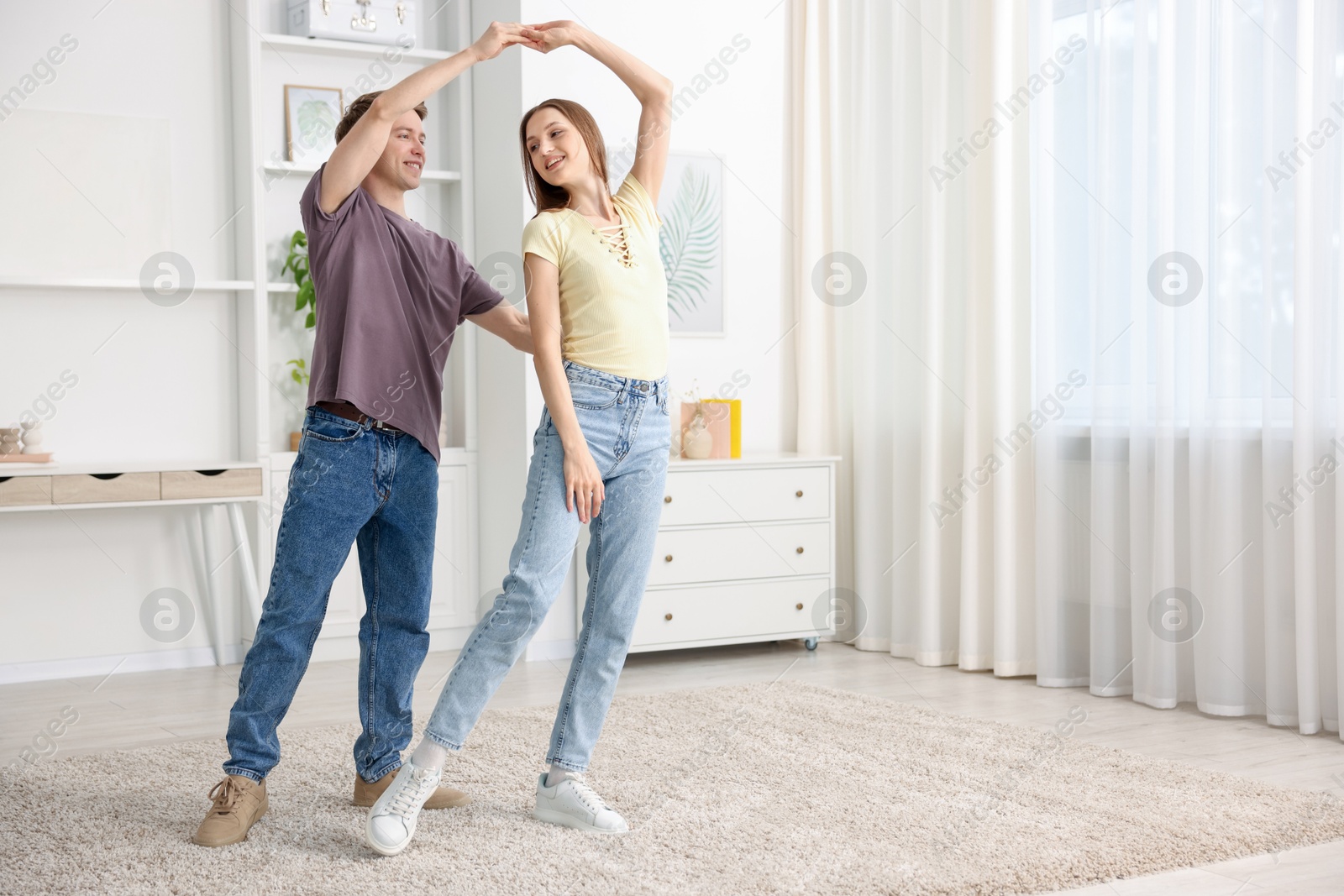 Happy young couple dancing together at home. Space for text Photo of Happy young couple dancing together at home. Space for text