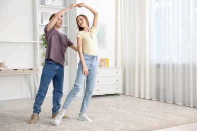 Photo of Happy young couple dancing together at home. Space for text
