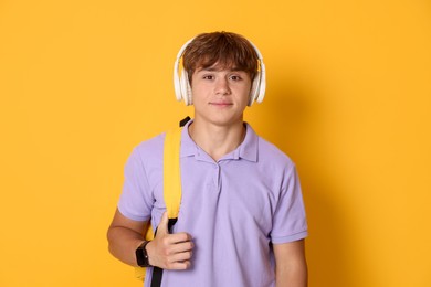Photo of Cute teenage boy listening to music on yellow background