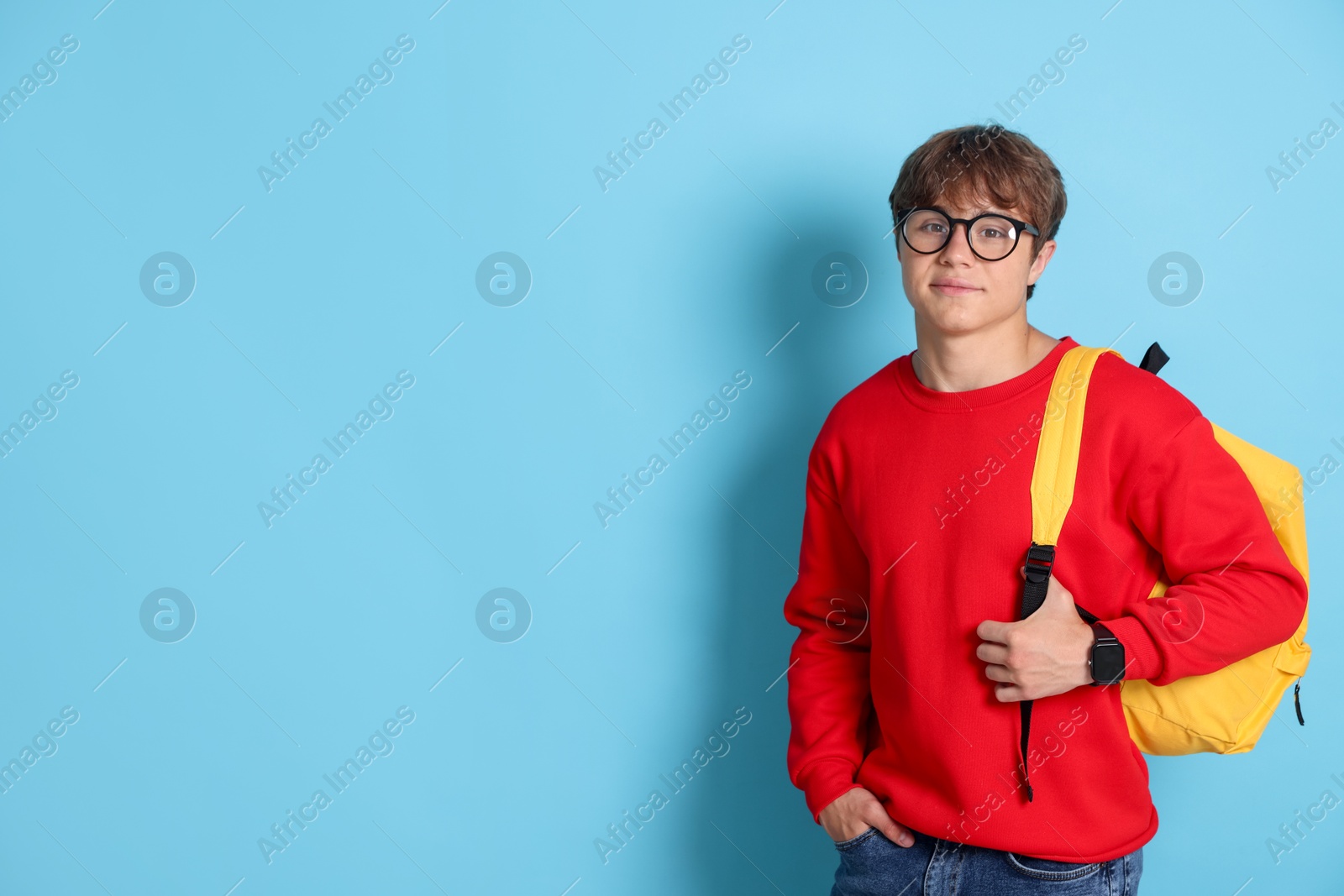 Cute teenage boy in glasses with backpack on light blue background. Space for text Photo of Cute teenage boy in glasses with backpack on light blue background. Space for text