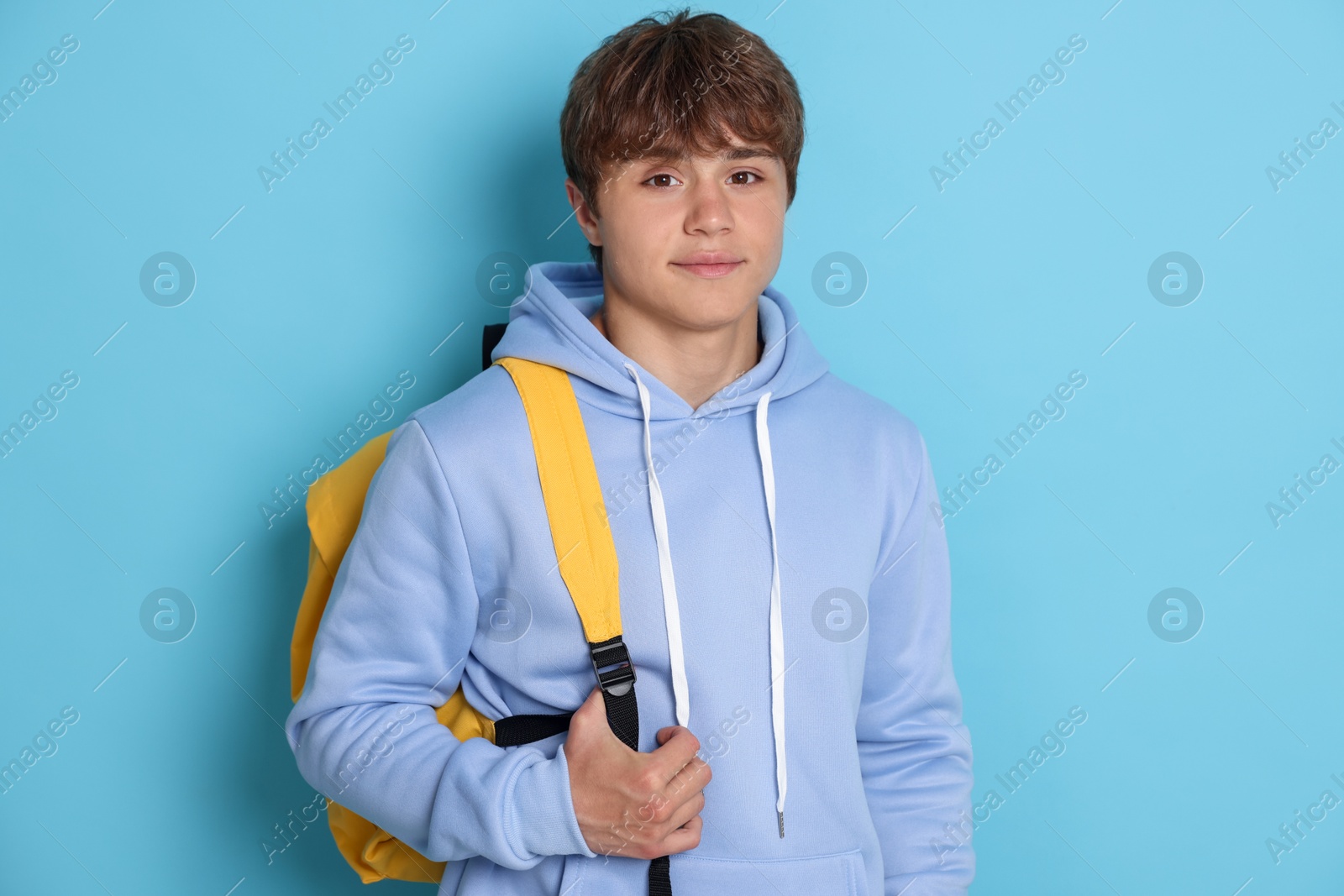 Portrait of cute teenage boy with backpack on light blue background Photo of Portrait of cute teenage boy with backpack on light blue background