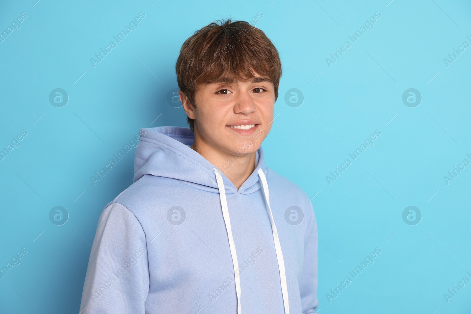Portrait of smiling teenage boy on light blue background Photo of Portrait of smiling teenage boy on light blue background