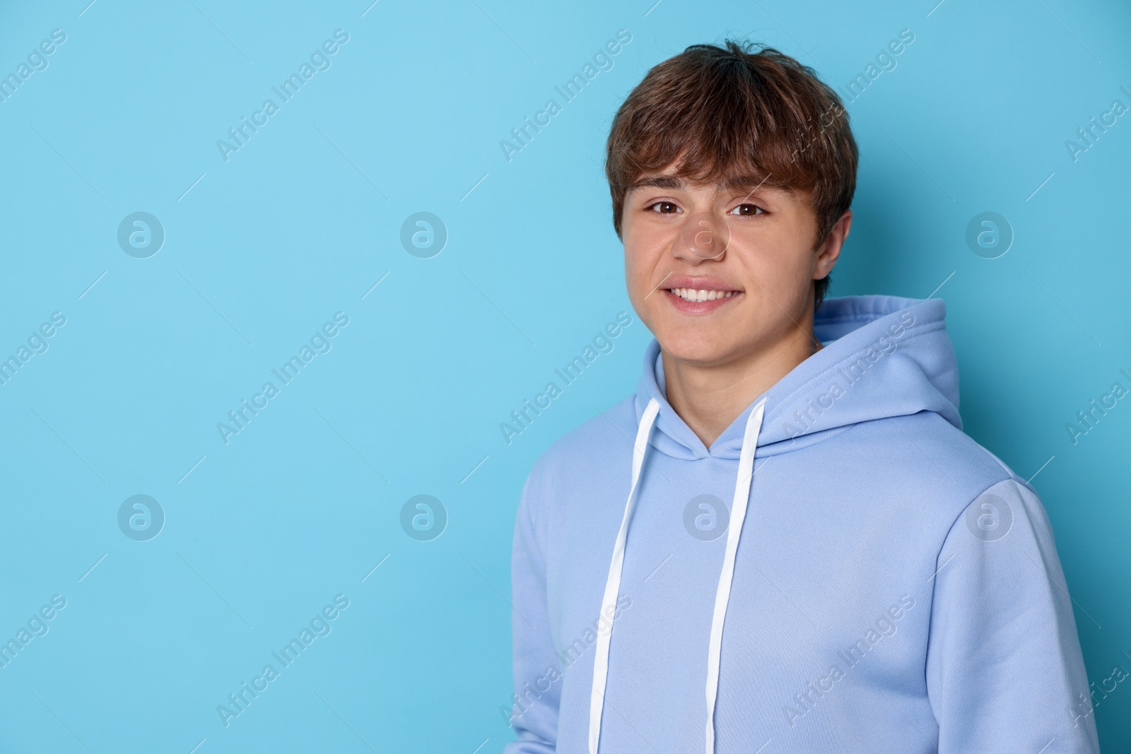 Portrait of smiling teenage boy on light blue background. Space for text Photo of Portrait of smiling teenage boy on light blue background. Space for text