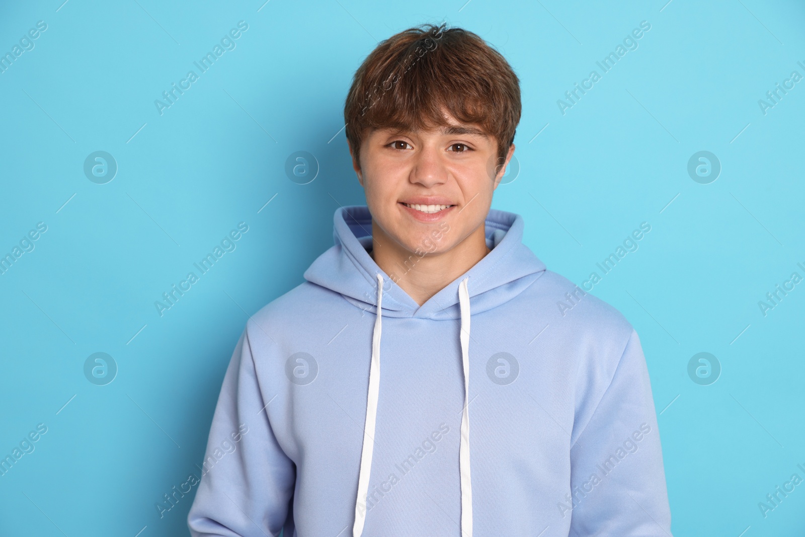 Portrait of smiling teenage boy on light blue background Photo of Portrait of smiling teenage boy on light blue background