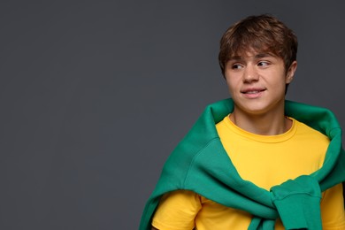 Photo of Smiling teenage boy on grey background. Space for text