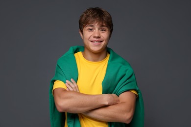 Photo of Portrait of smiling teenage boy with crossed arms on grey background