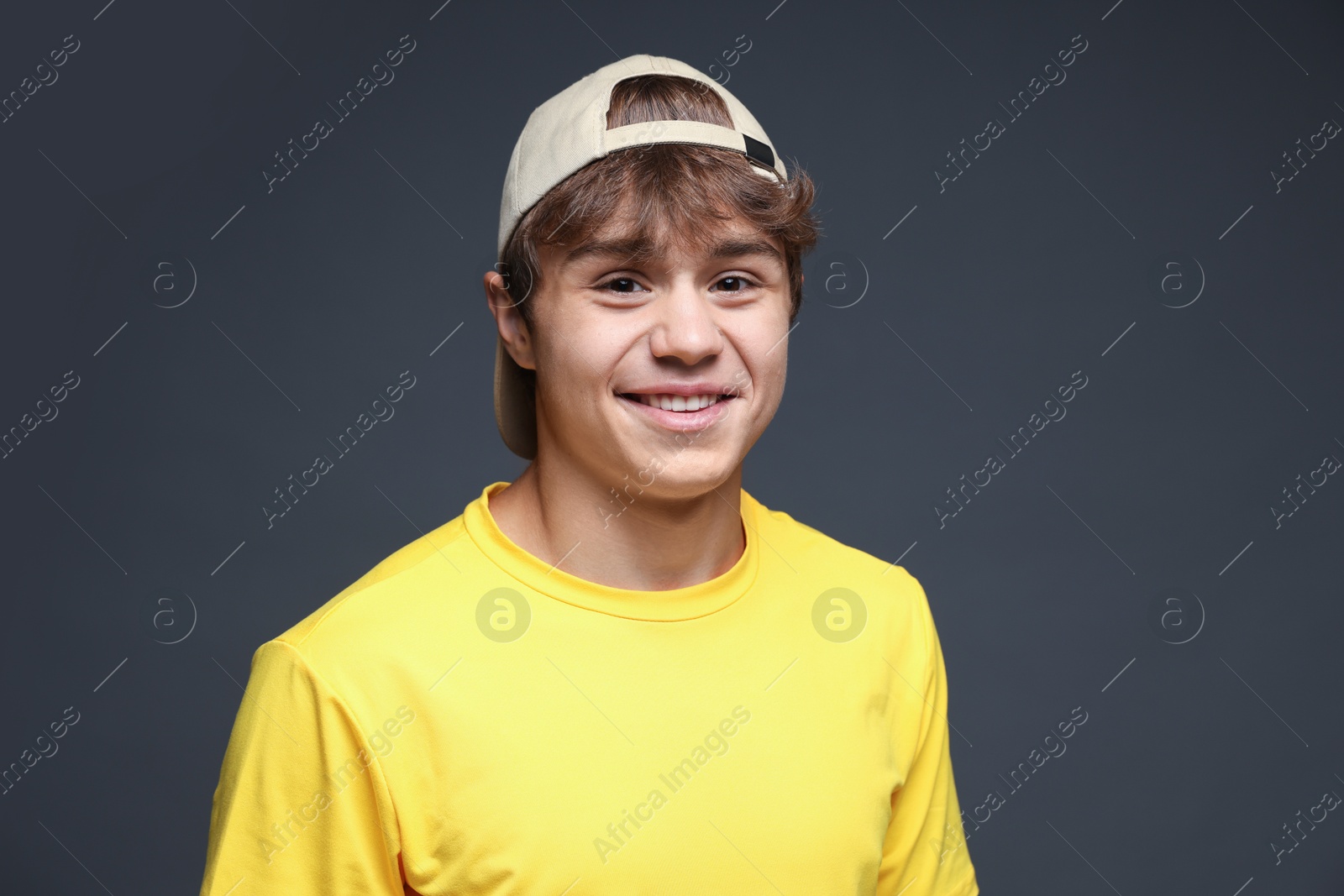 Portrait of smiling teenage boy in baseball hat on grey background Photo of Portrait of smiling teenage boy in baseball hat on grey background