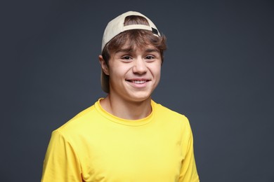 Photo of Portrait of smiling teenage boy in baseball hat on grey background