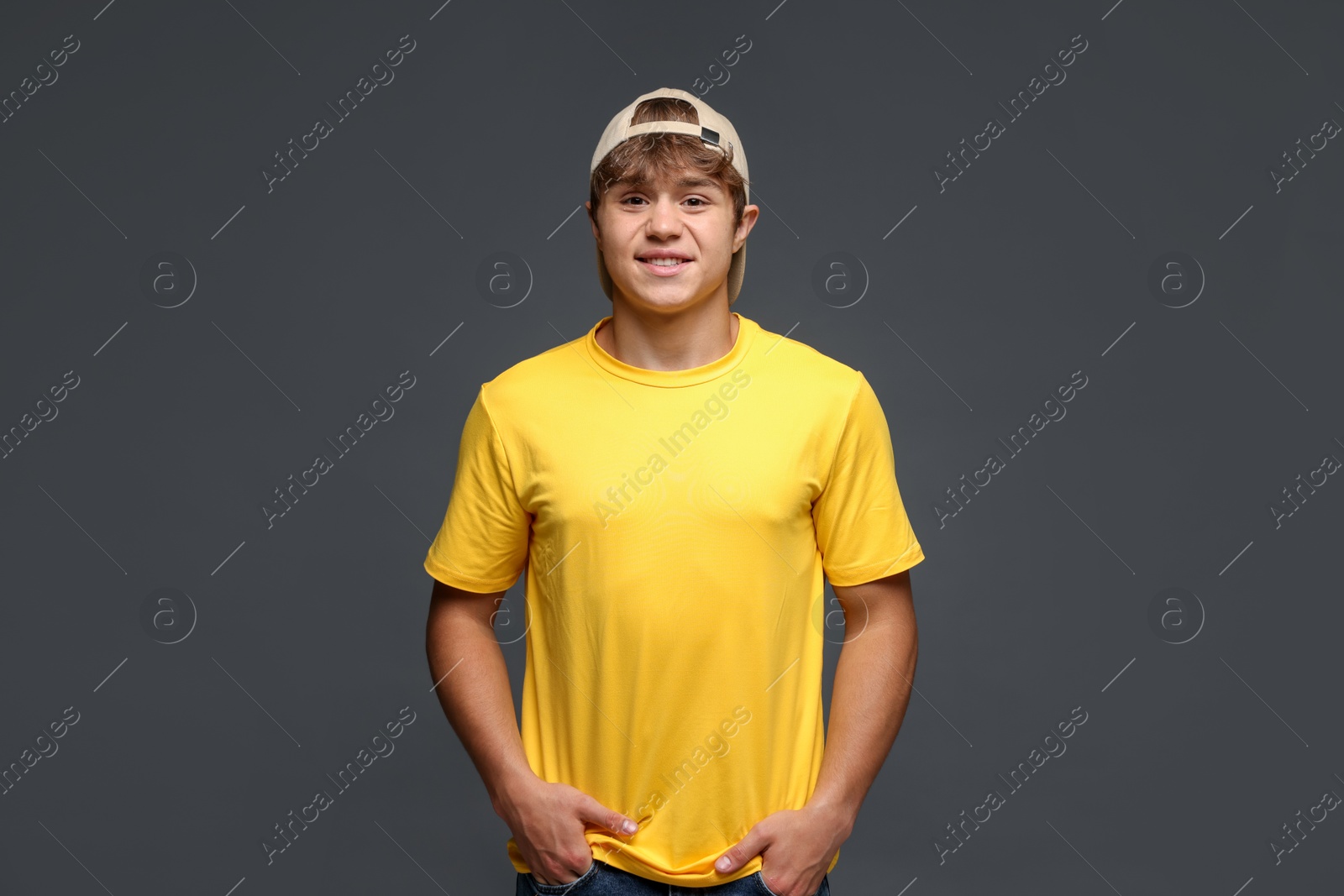 Photo of Portrait of smiling teenage boy in baseball hat on grey background