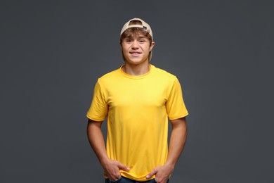 Photo of Portrait of smiling teenage boy in baseball hat on grey background