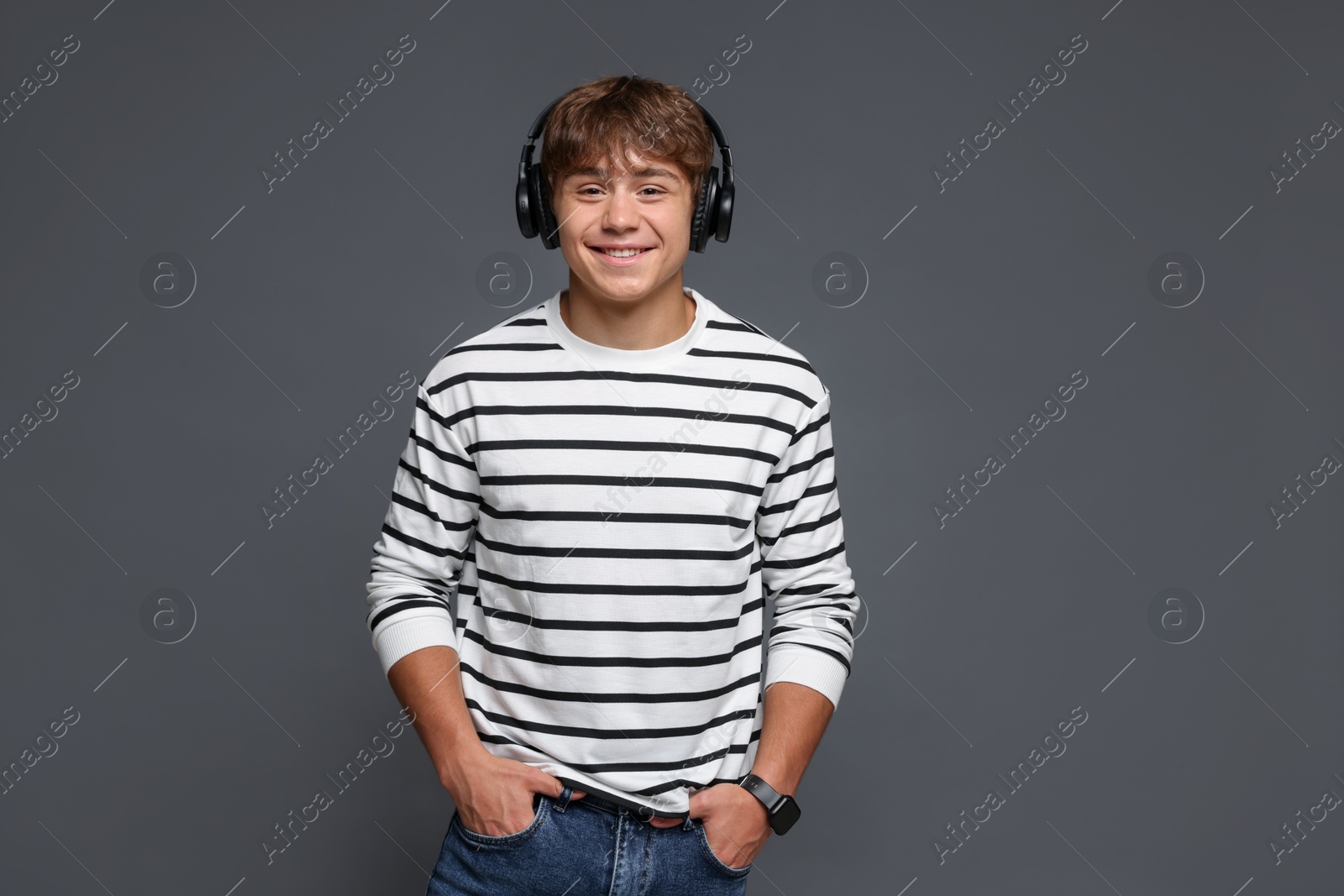 Portrait of smiling teenage boy in headphones on grey background Photo of Portrait of smiling teenage boy in headphones on grey background