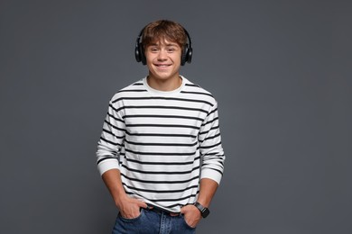 Photo of Portrait of smiling teenage boy in headphones on grey background