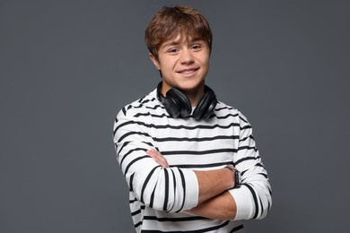 Photo of Portrait of smiling teenage boy with crossed arms on grey background
