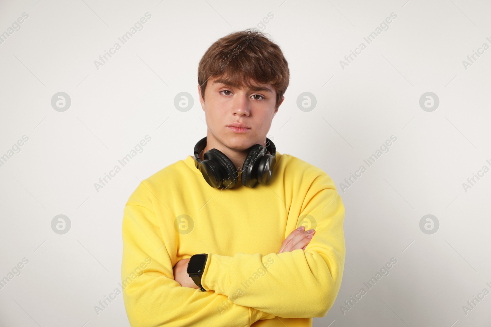 Portrait of teenage boy with crossed arms on light grey background Photo of Portrait of teenage boy with crossed arms on light grey background