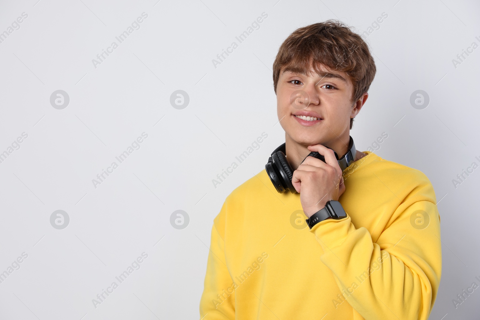 Portrait of smiling teenage boy with headphones on light grey background. Space for text Photo of Portrait of smiling teenage boy with headphones on light grey background. Space for text