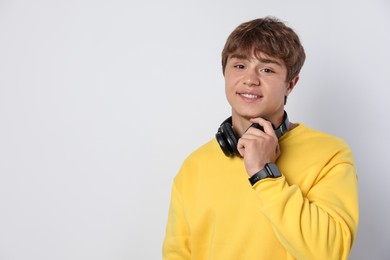 Photo of Portrait of smiling teenage boy with headphones on light grey background. Space for text