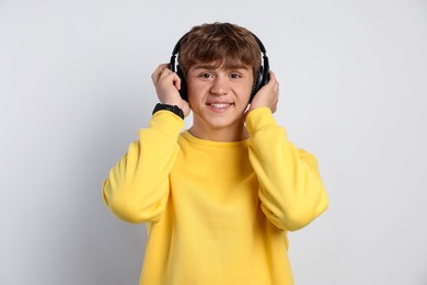Photo of Portrait of smiling teenage boy in headphones on light grey background