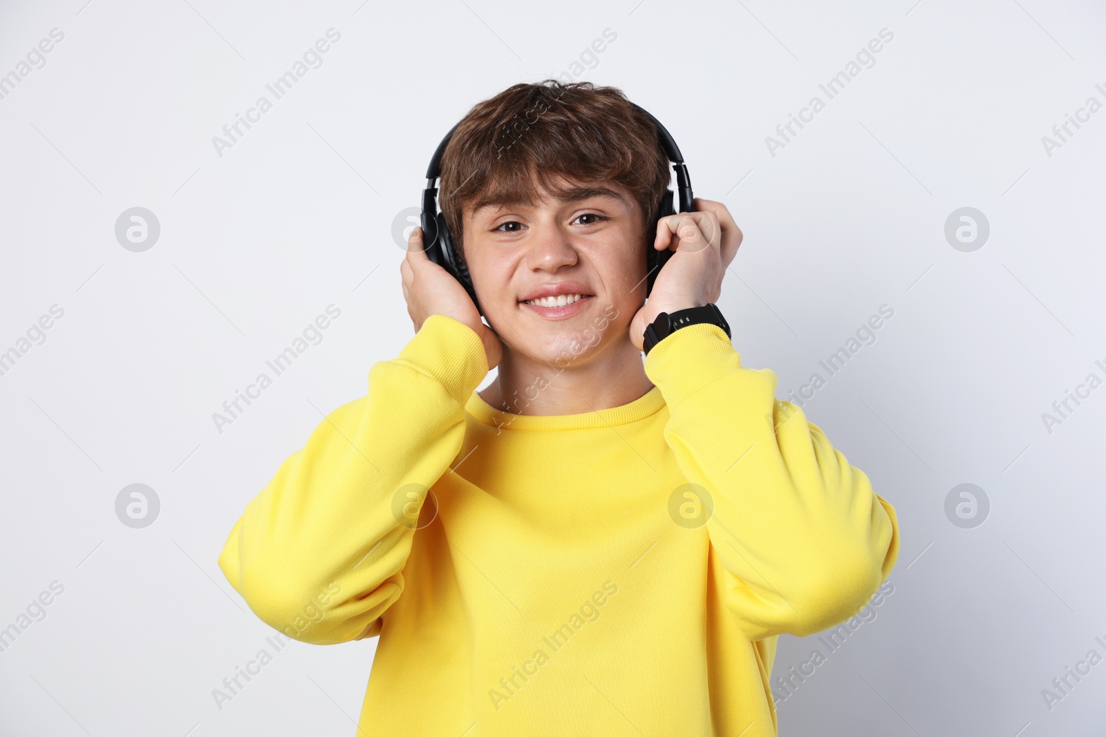 Portrait of smiling teenage boy in headphones on light grey background Photo of Portrait of smiling teenage boy in headphones on light grey background