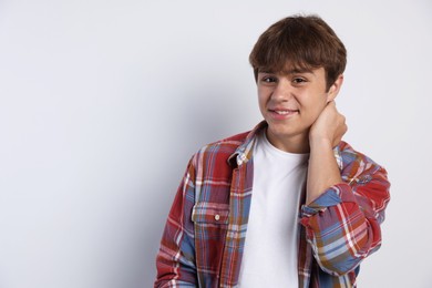 Photo of Portrait of smiling teenage boy on light grey background. Space for text