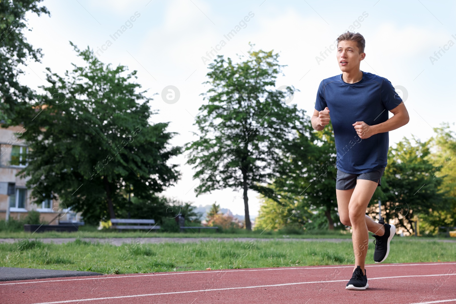 Sporty man running at stadium, space for text Photo of Sporty man running at stadium, space for text