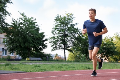 Photo of Sporty man running at stadium, space for text
