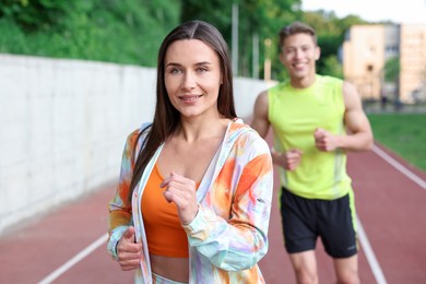 Photo of Sporty couple running at stadium, selective focus
