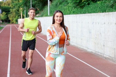 Photo of Sporty couple running at stadium. Healthy lifestyle