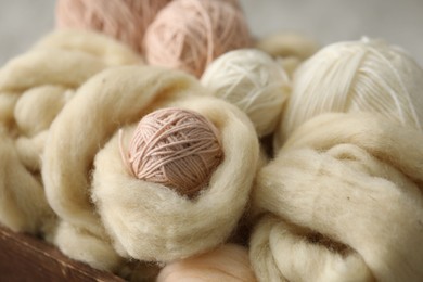 Photo of Soft felting wool and knitting yarn in wooden basket, closeup