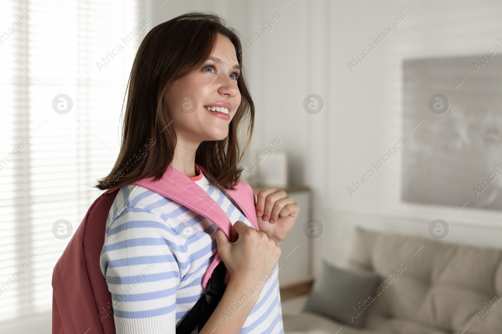 Smiling teenage girl with backpack at home. Space for text Photo of Smiling teenage girl with backpack at home. Space for text