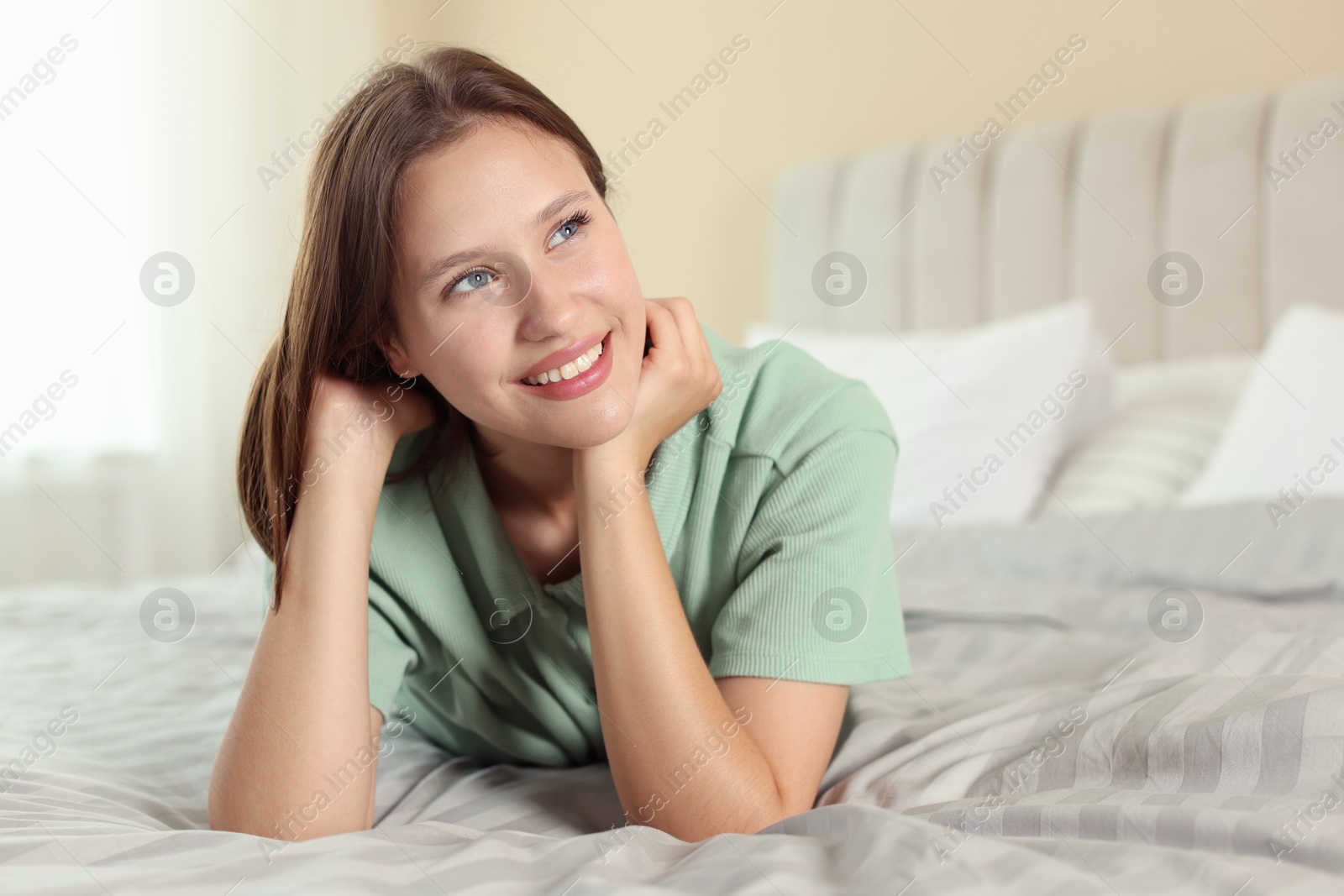 Portrait of smiling teenage girl on bed at home Photo of Portrait of smiling teenage girl on bed at home