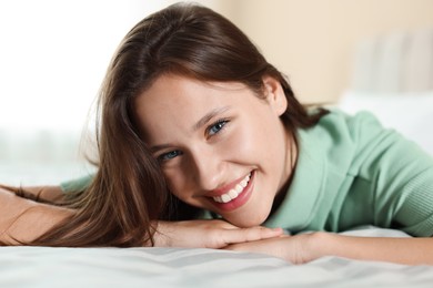 Photo of Portrait of smiling teenage girl on bed at home, closeup