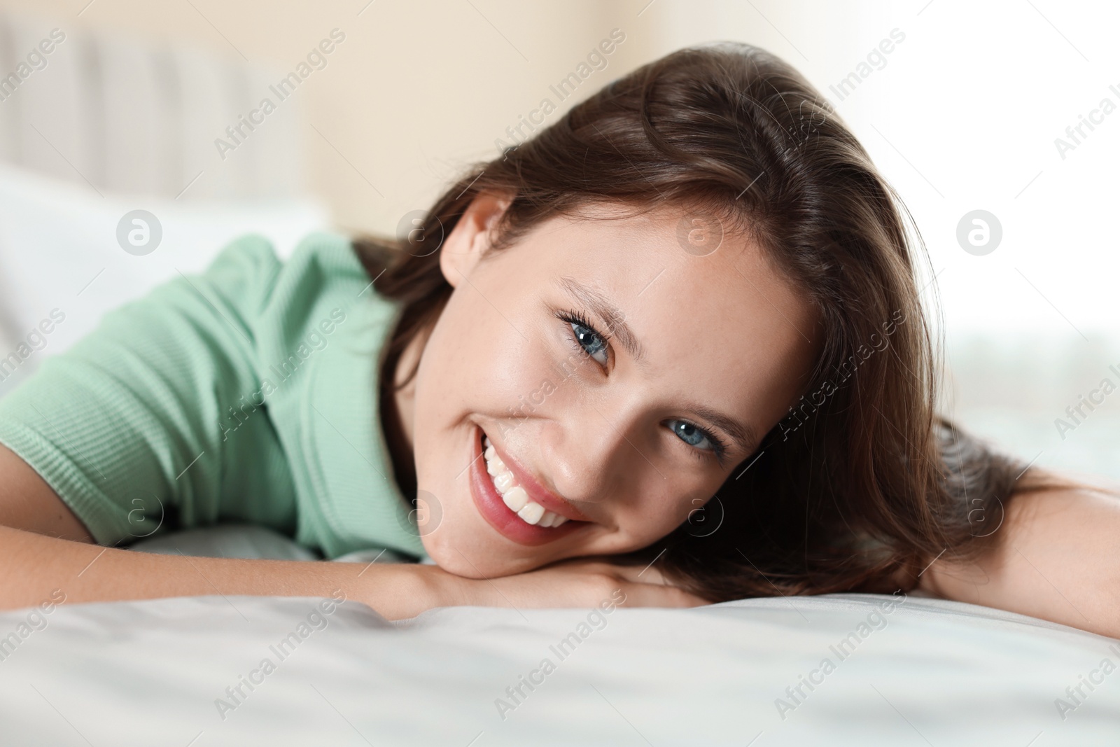 Photo of Portrait of smiling teenage girl on bed at home, closeup