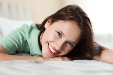 Photo of Portrait of smiling teenage girl on bed at home, closeup
