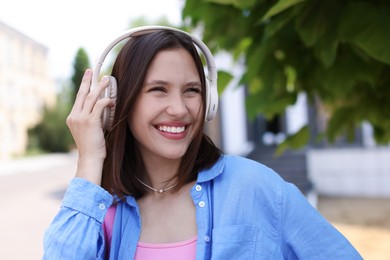 Photo of Portrait of smiling teenage girl in headphones outdoors