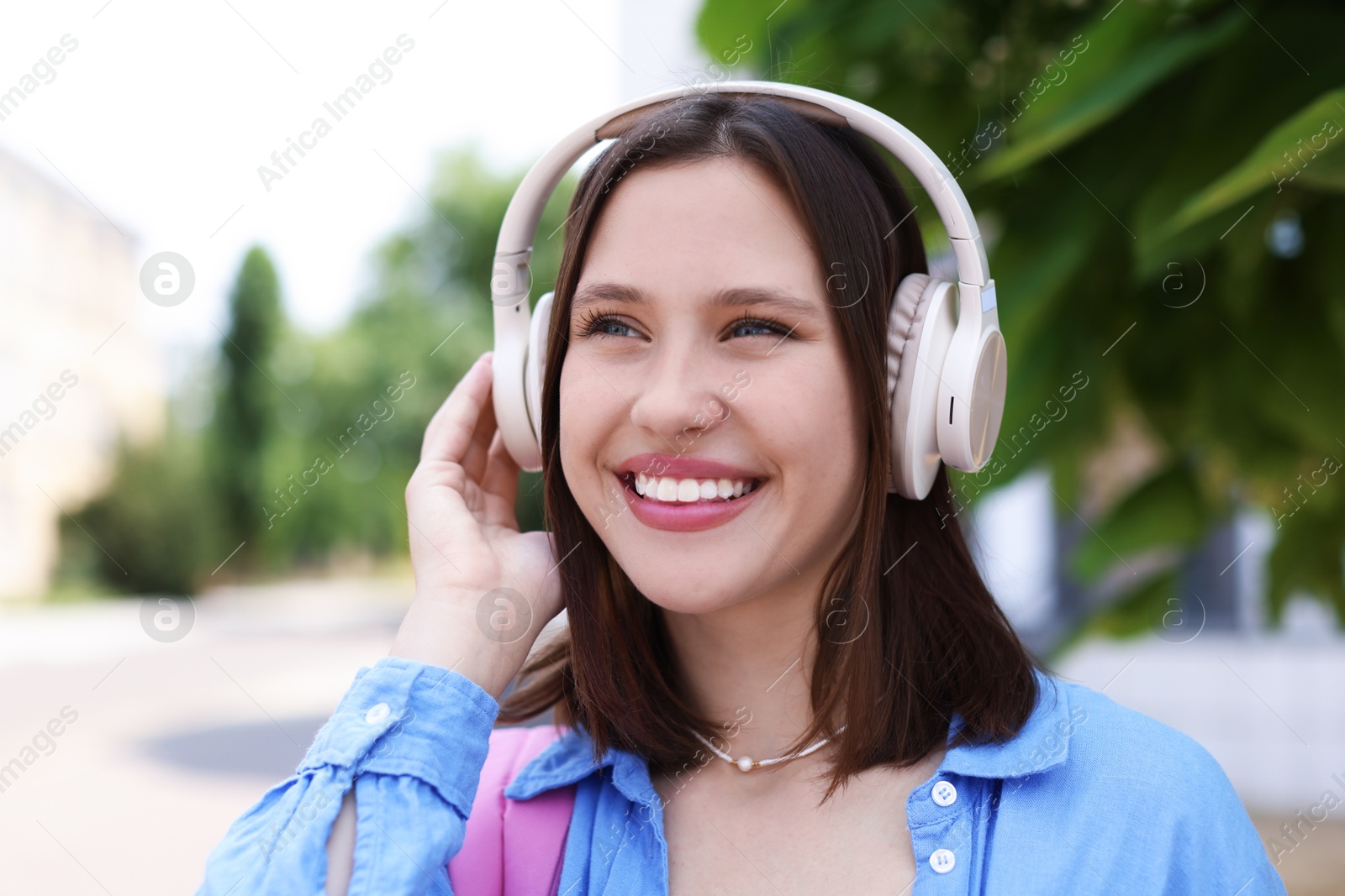 Portrait of smiling teenage girl in headphones outdoors Photo of Portrait of smiling teenage girl in headphones outdoors