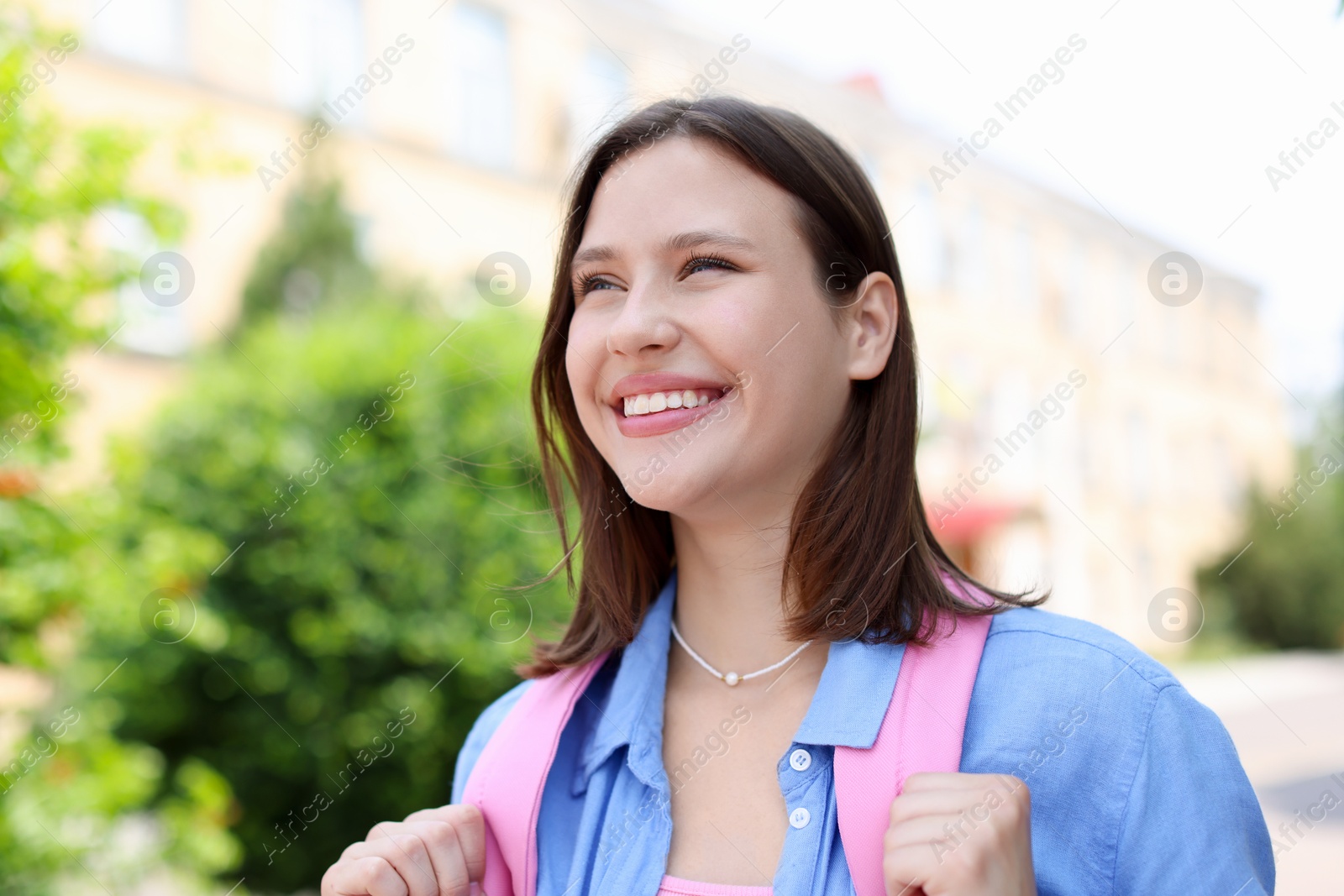 Smiling teenage girl on city street, low angle view Photo of Smiling teenage girl on city street, low angle view