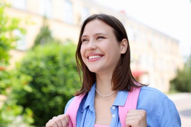 Photo of Smiling teenage girl on city street, low angle view