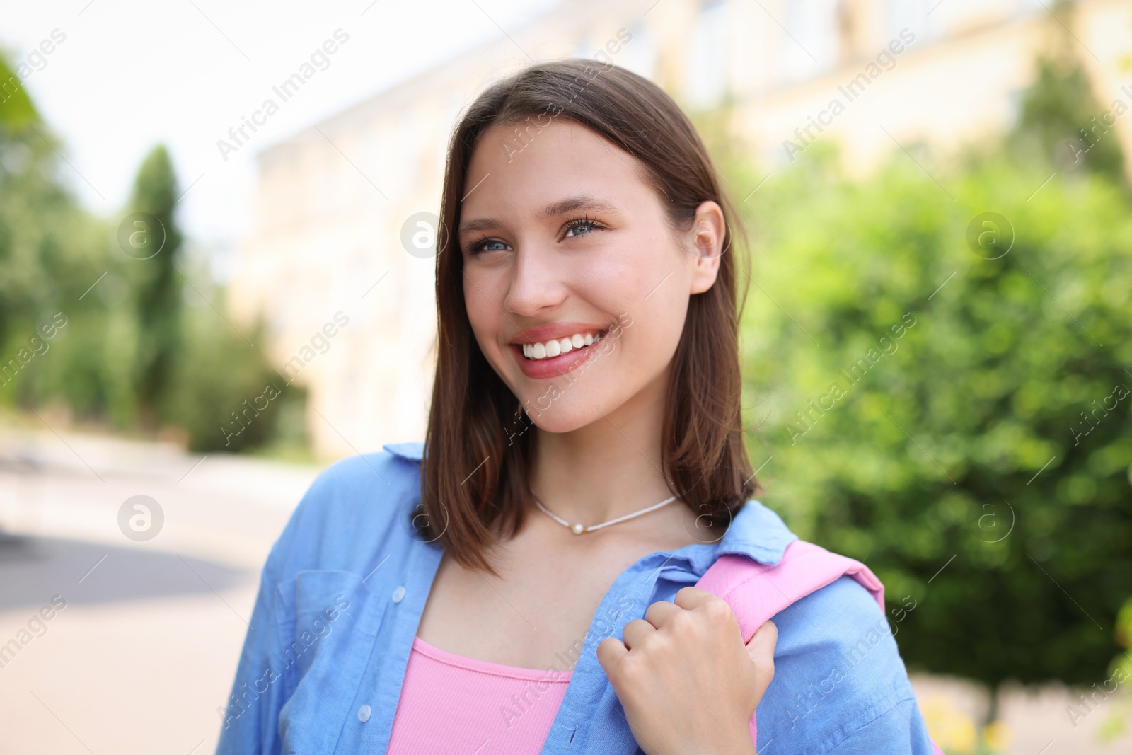 Portrait of smiling teenage girl on city street Photo of Portrait of smiling teenage girl on city street