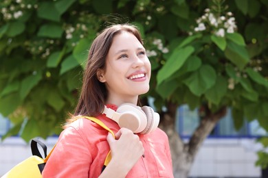 Photo of Smiling teenage girl with headphones on city street