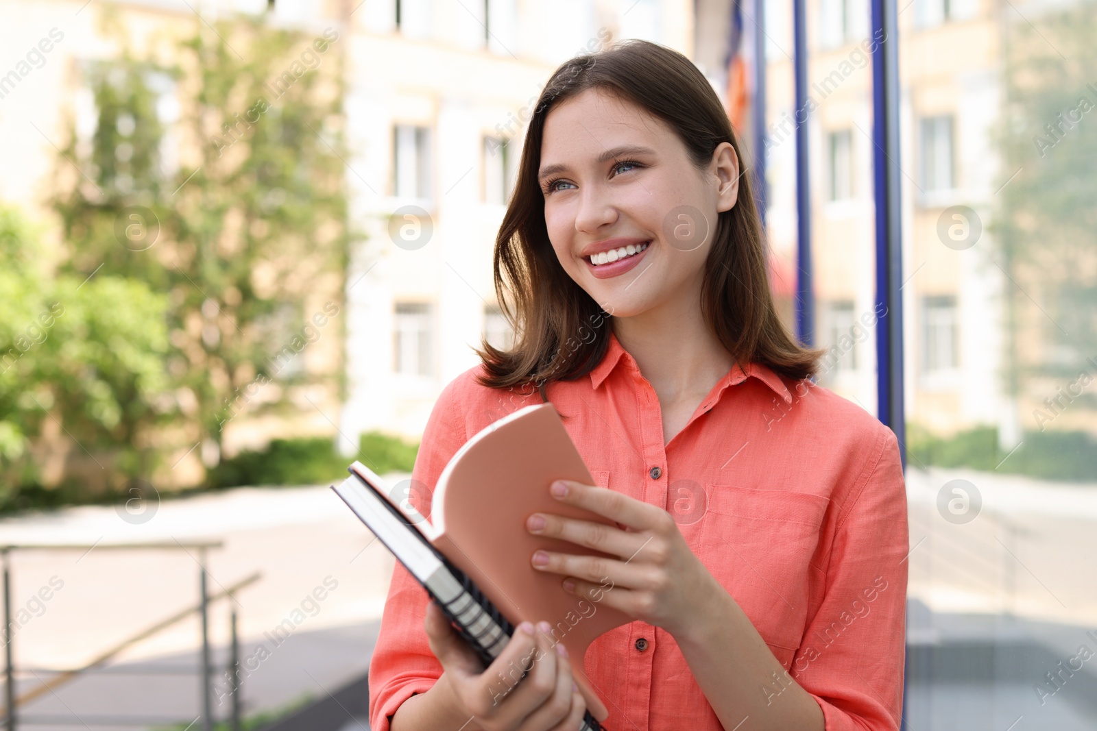 Smiling teenage girl with notepads on city street Photo of Smiling teenage girl with notepads on city street