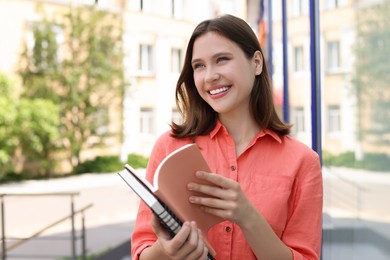 Photo of Smiling teenage girl with notepads on city street