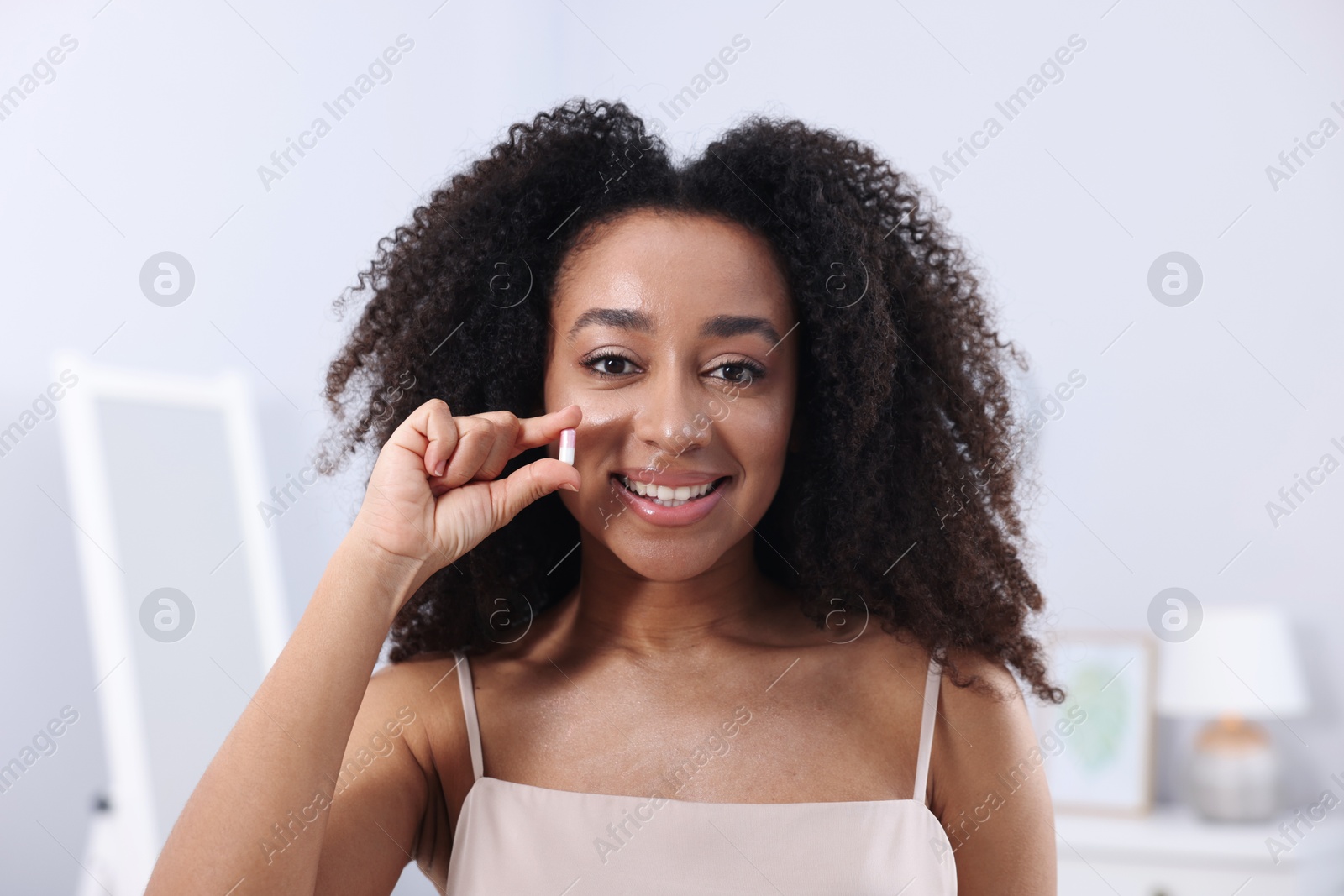 Beautiful Brazilian woman with collagen pill indoors Photo of Beautiful Brazilian woman with collagen pill indoors