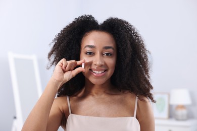 Photo of Beautiful Brazilian woman with collagen pill indoors