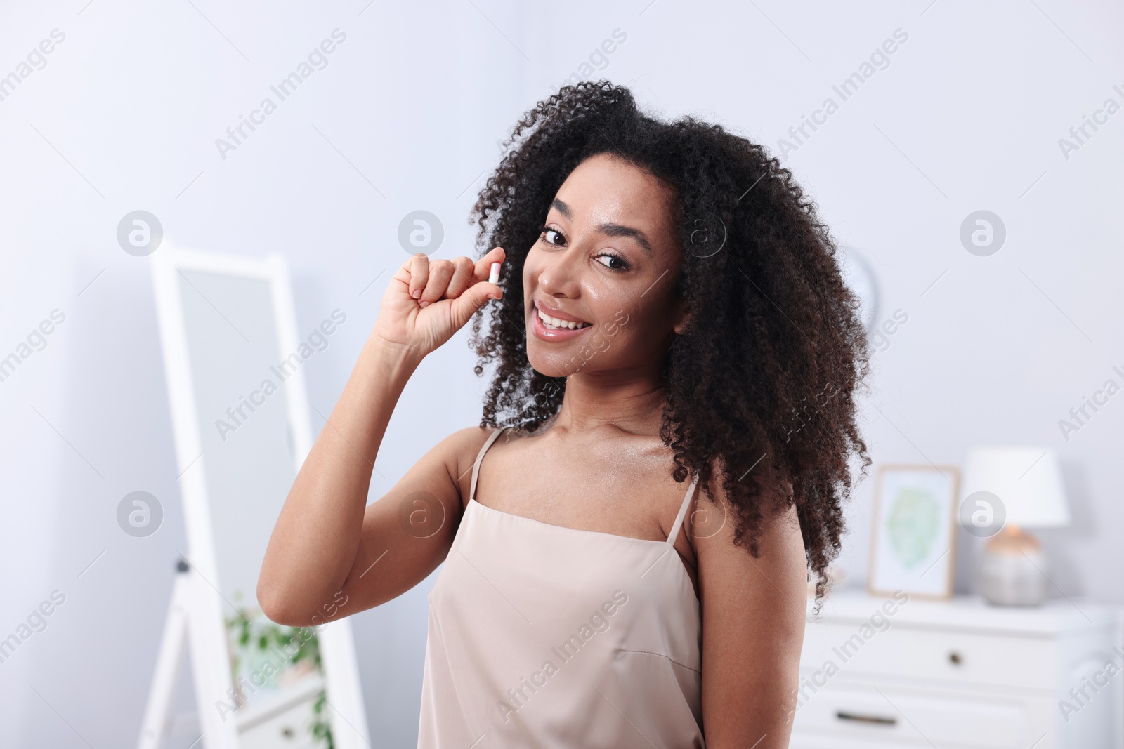 Beautiful Brazilian woman with collagen pill indoors Photo of Beautiful Brazilian woman with collagen pill indoors