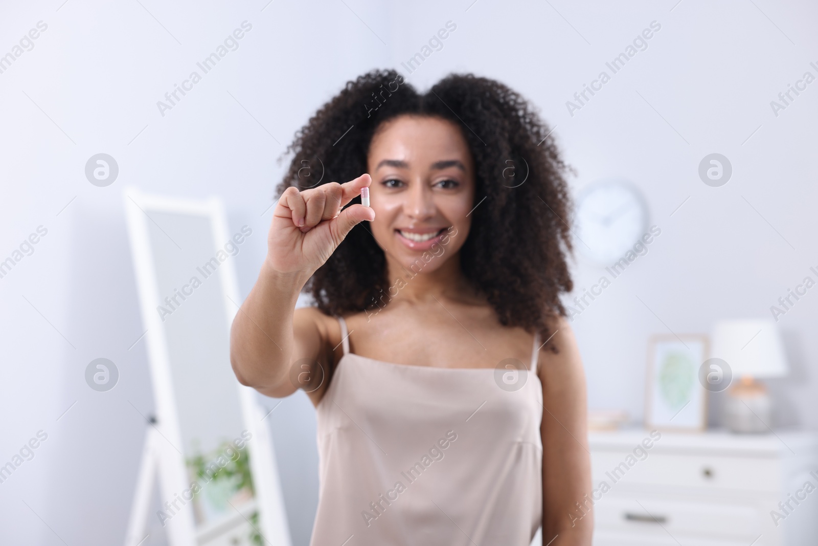 Beautiful Brazilian woman with collagen pill indoors, selective focus Photo of Beautiful Brazilian woman with collagen pill indoors, selective focus