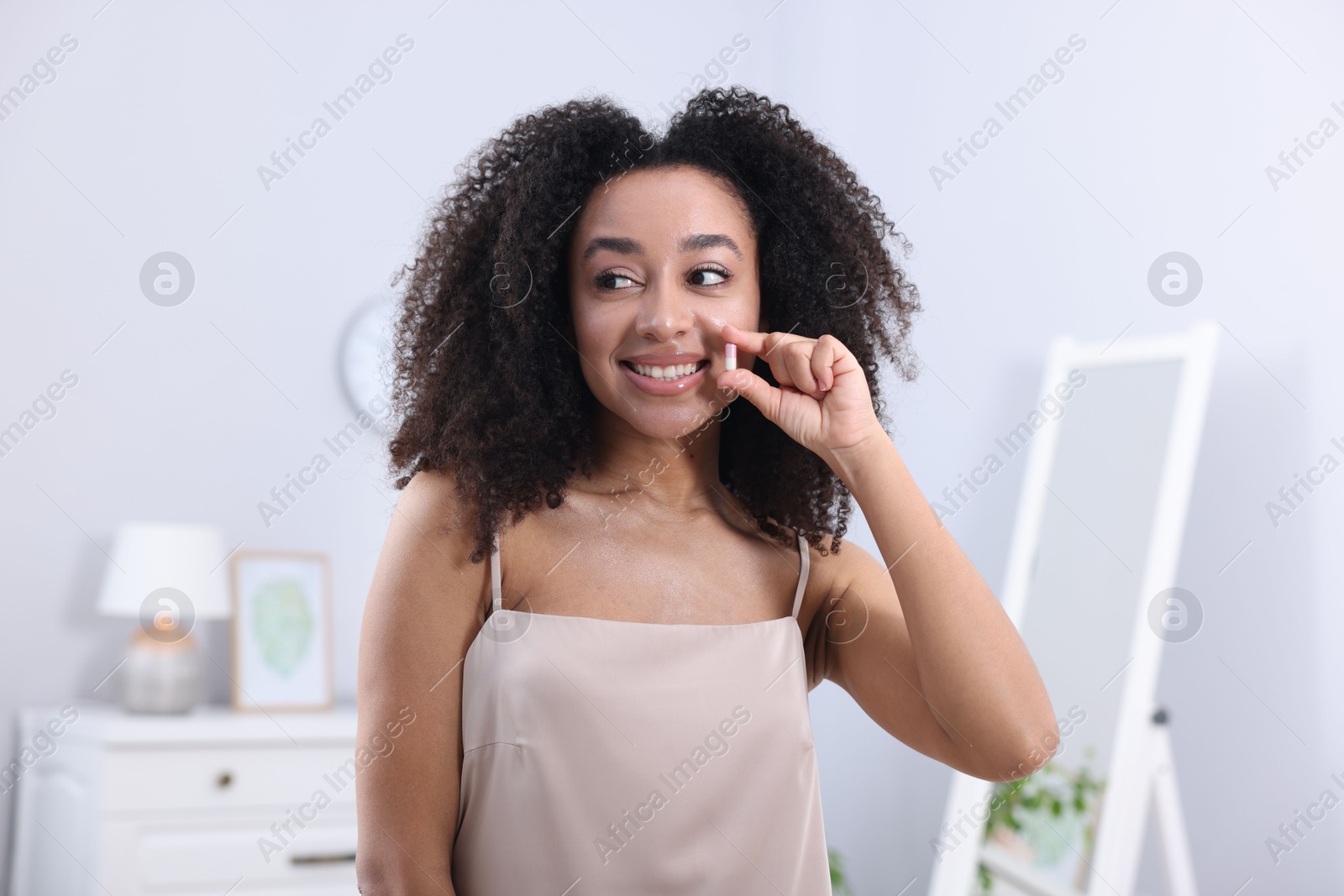 Beautiful Brazilian woman with collagen pill indoors Photo of Beautiful Brazilian woman with collagen pill indoors