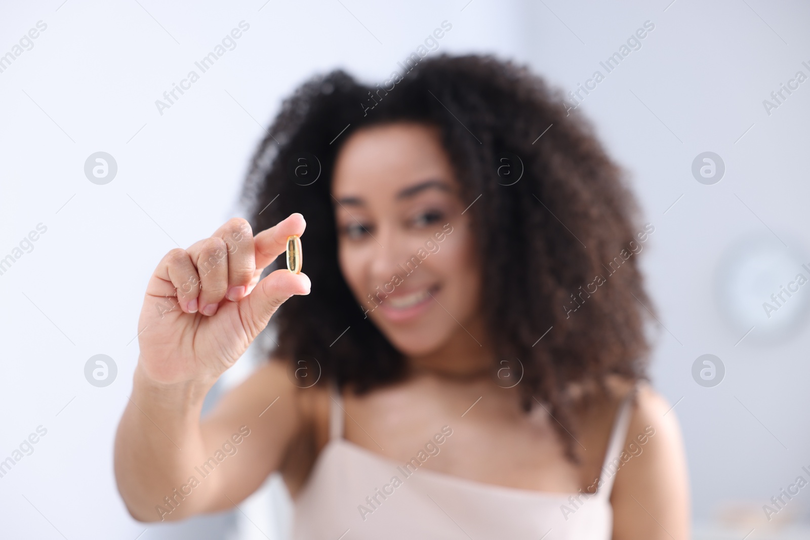 Beautiful Brazilian woman with collagen pill indoors, selective focus Photo of Beautiful Brazilian woman with collagen pill indoors, selective focus