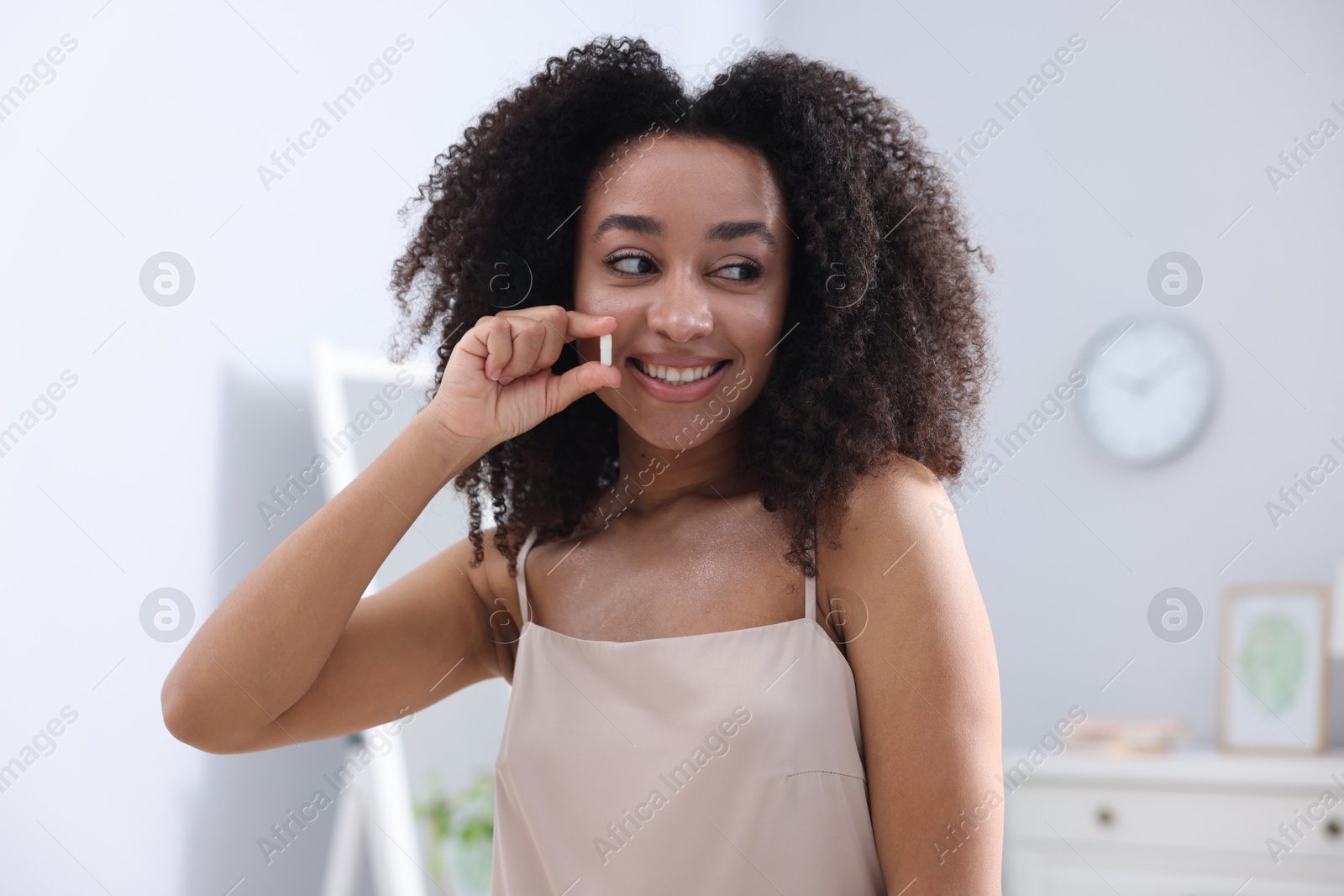 Beautiful Brazilian woman with collagen pill indoors Photo of Beautiful Brazilian woman with collagen pill indoors